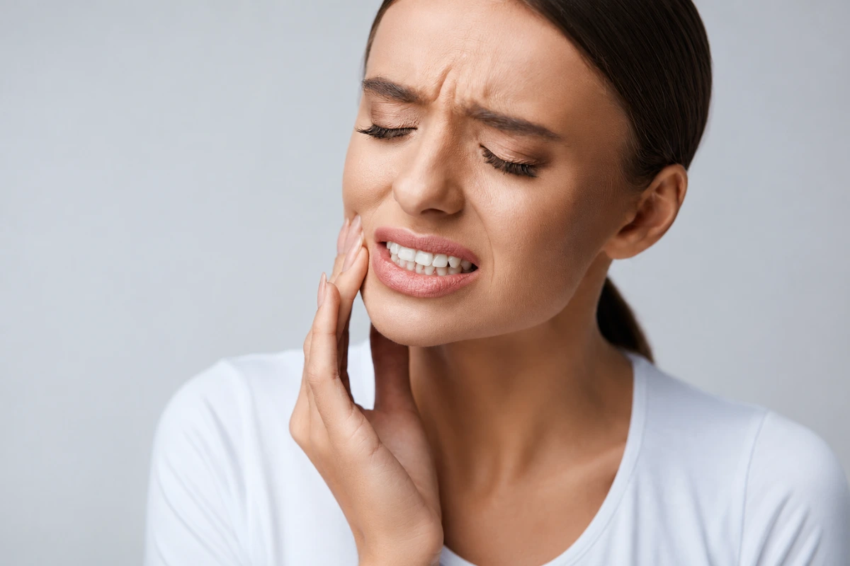 Woman experiencing severe tooth pain, a sign that it's time to visit a dental clinic immediately.