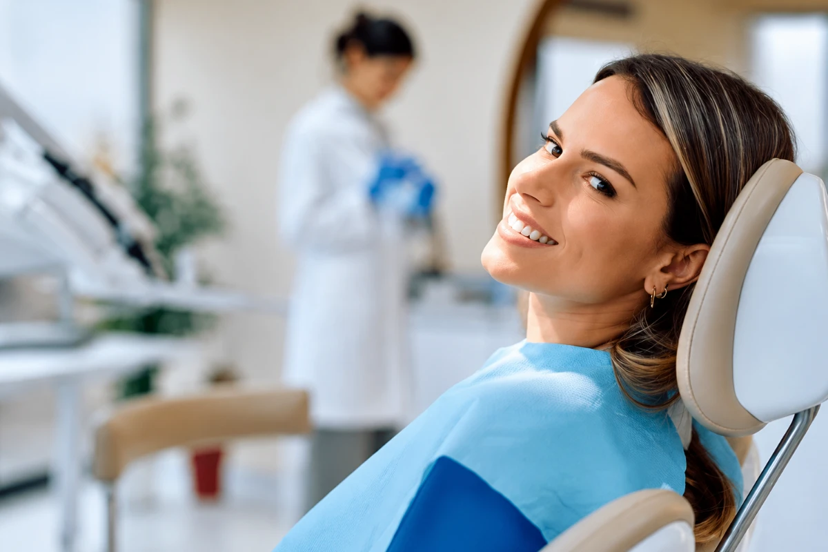 Smiling female patient sitting comfortably in a modern dental chair during a tooth preservation consultation.